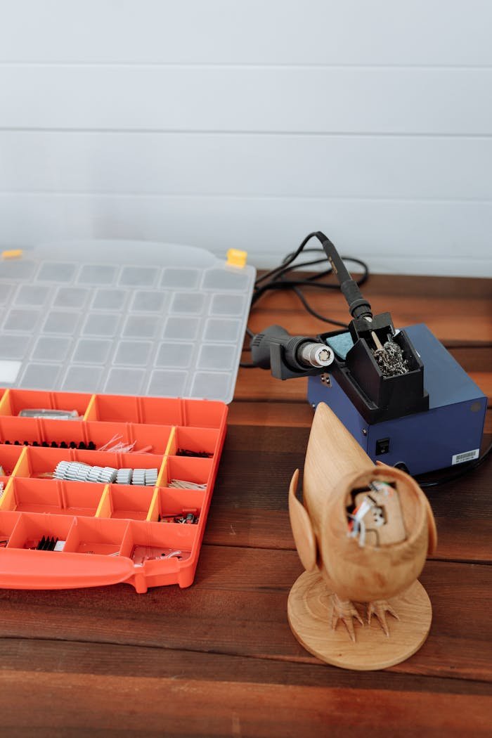 A soldering station with tools and components on a wooden table for electronics work.